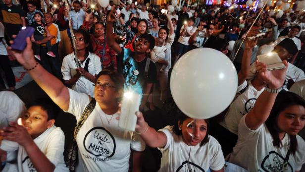Eine Menschenmenge hält Kerzen und Ballons bei einer Mahnwache für MH370.