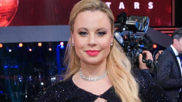 Eine Frau in Abendgarderobe posiert vor dem „Dancing Stars“-Logo.