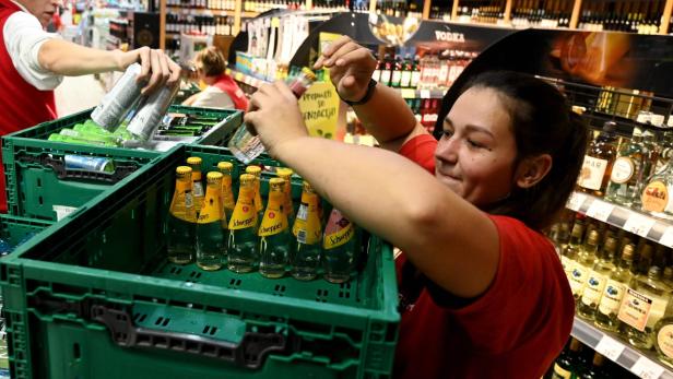 Eine Supermarkt-Mitarbeiterin räumt Schweppes-Flaschen weg.