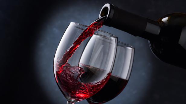 Rotwein wird in zwei Gläser eingeschenkt.