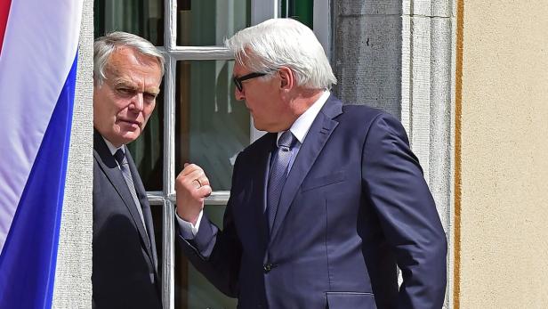 Frank-Walter Steinmeier im Gespräch mit Michel Barnier vor einem Fenster.
