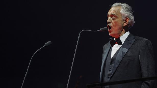 Andrea Bocelli singt auf einer Bühne in ein Mikrofon.
