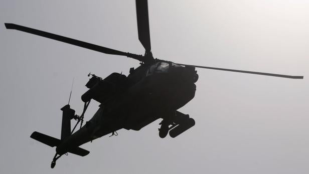 Die Silhouette eines Kampfhubschraubers am Himmel.