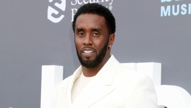 Sean „Diddy“ Combs trägt einen weißen Anzug vor einem Billboard Music Awards-Hintergrund.