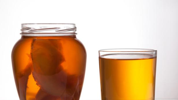 Ein Glas und ein Glas mit Kombucha stehen auf einem Tisch.