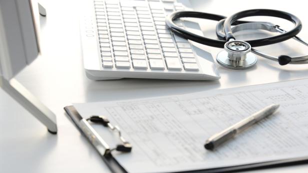 Doctor's desk with stethoscope, clipboard, and computer 