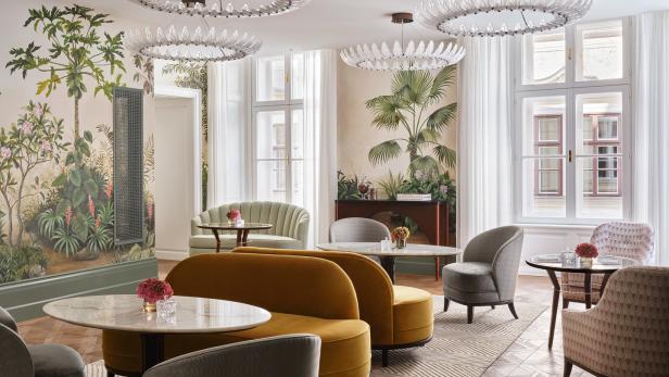 Ein elegant eingerichteter Raum mit floralen Wandmalereien, Sofas und Sesseln um kleine Tische.