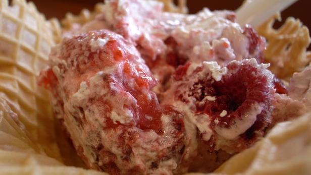 Ein Waffelbecher gefüllt mit Himbeereis und Schlagsahne.