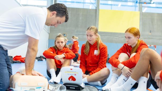 Ein Mitarbeiter vom Roten Kreuz zeigt Fußballerinnen von der ÖFB-Frauenakademie anhand einer Puppe, wie man einen Menschen reanimiert