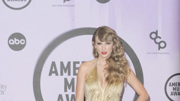 Taylor Swift posiert in einem goldenen Overall bei den American Music Awards.