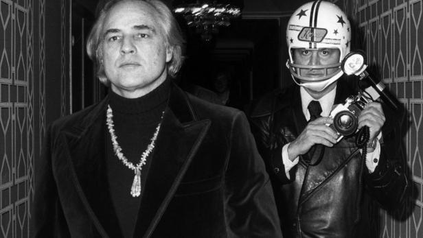 Marlon Brando und ein Fotograf mit Footballhelm in einem Flur.