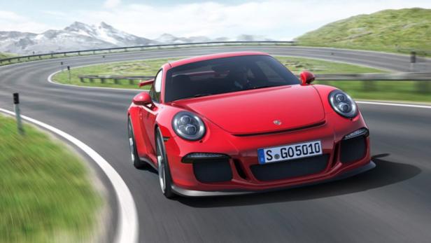 Ein roter Porsche fährt auf einer kurvenreichen Straße in den Bergen.