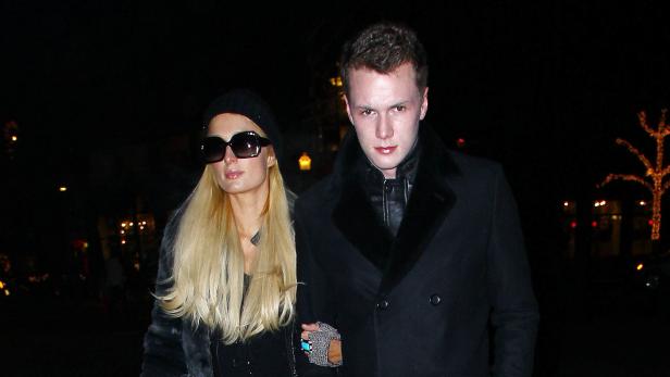 Paris Hilton geht mit einem Mann in dunkler Kleidung Arm in Arm.