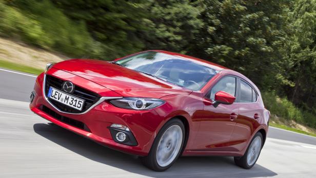 Ein roter Mazda 3 fährt auf einer Landstraße.