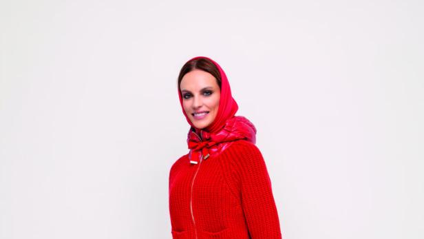 Eine Frau in roter Kleidung trägt eine große Tasche mit Geschenken.