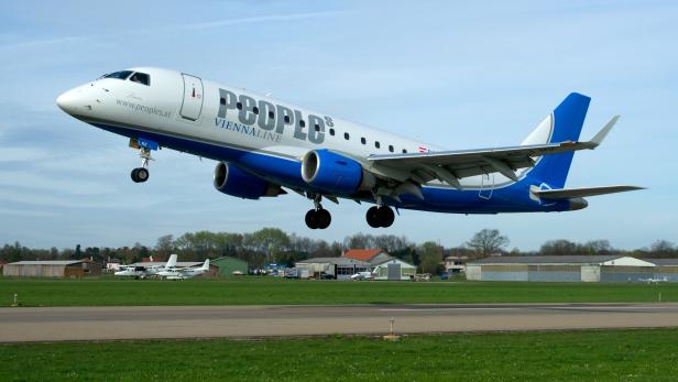 Ein Flugzeug der People's Viennaline startet von einer grünen Landebahn.