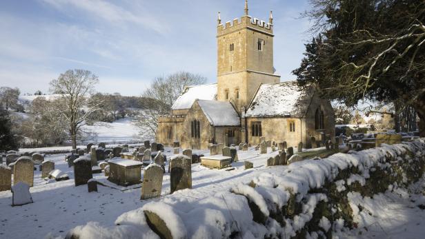 Eine verschneite Kirche mit Friedhof im Winter.