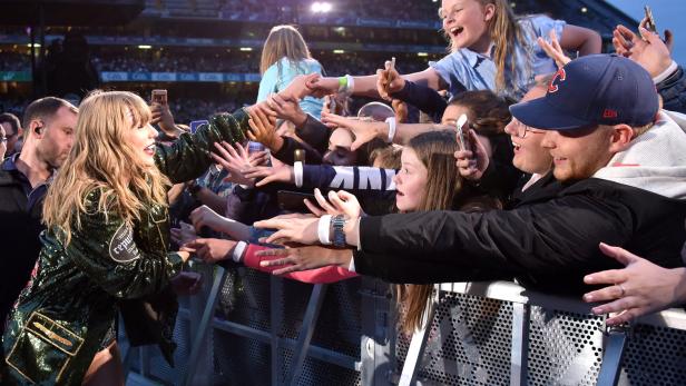 Taylor Swift interagiert während eines Konzerts mit Fans an der Absperrung.