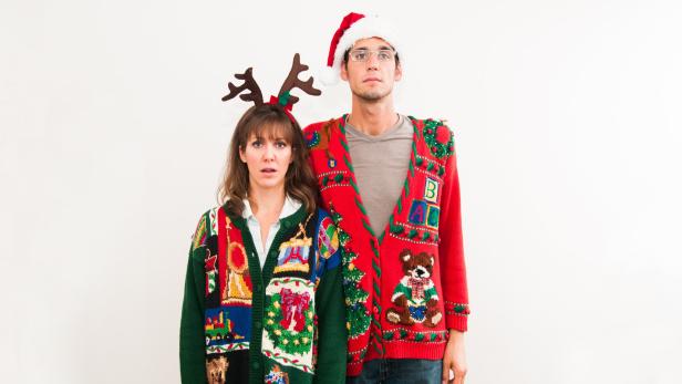 Ein Paar trägt Weihnachtspullover und Stirnbänder mit Weihnachtsmotiven.