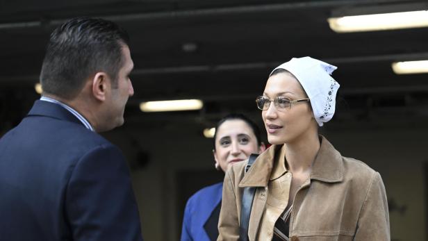 Bella Hadid hält einen Kaffeebecher in der Hand und spricht mit einem Mann.