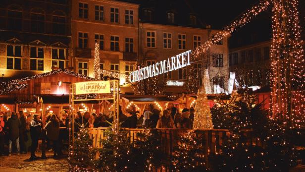 Ein belebter Weihnachtsmarkt mit Lichtern und Menschen in der Nacht.