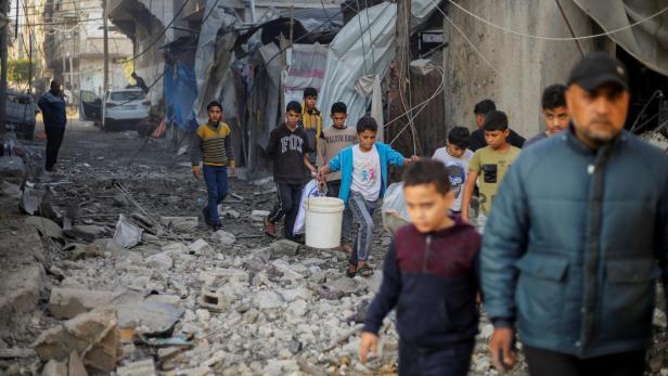 Palestinian children carry items as they walk at the site of Israeli strikes in Khan Younis