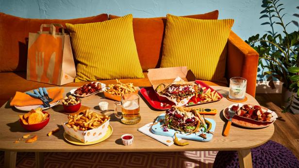 Ein Tisch ist mit verschiedenen Speisen wie Döner, Pommes und Currywurst gedeckt.