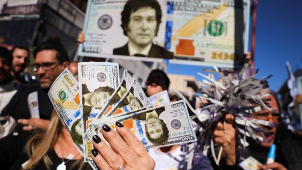 Milei-Wahlkampf in Buenos Aires, Menschen halten Dollarscheine mit seinem Konterfei in der Mitte in die Höhe