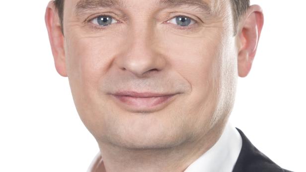 Porträt eines Mannes mit blau-grauen Augen in einem schwarzen Anzug.