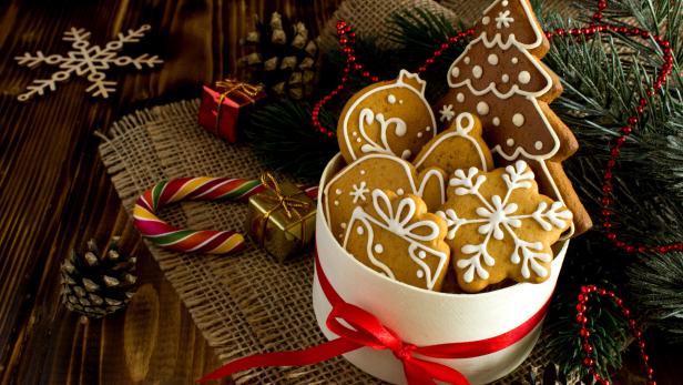 Lebkuchen in einer weißen Schachtel mit rotem Band auf einem Holztisch.