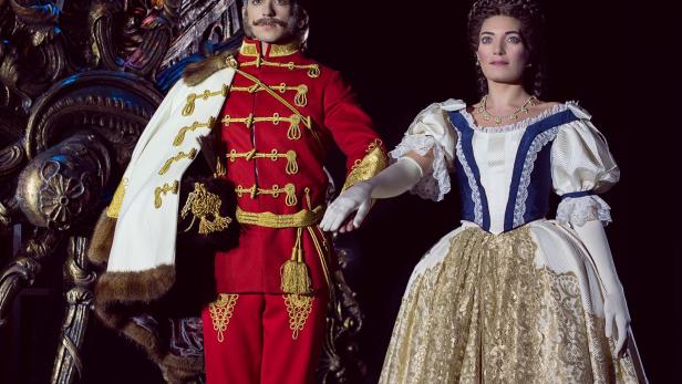 Ein Mann mit Schnurrbart und eine Frau in historischen Kostümen stehen nebeneinander.