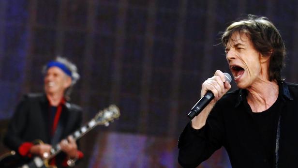 Mick Jagger singt mit einem Mikrofon in der Hand, während Keith Richards Gitarre spielt.