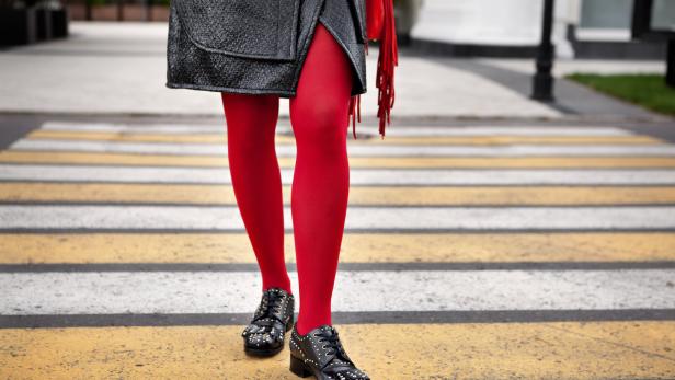 Eine Person mit roten Strumpfhosen überquert einen Zebrastreifen.
