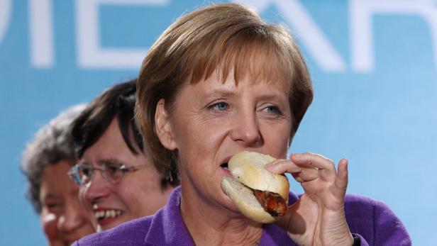 epa01862065 German Chancellor Angela Merkel of CDU (Christian Democrats) bites into a Thurinigian &#039;Bratwurst&#039; during an election campaign appearance in Erfurt, Germany, 15 September 2009. Mrs Merkel is currently touring Germany in the so-called &#039;Rheingold-Express&#039; historic train. EPA/OLIVER BERG