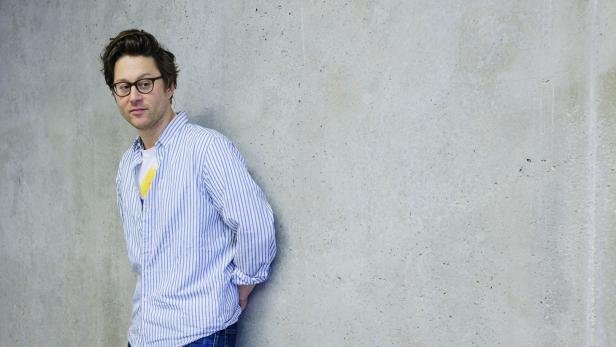 Arthur Arbesser lehnt an einer grauen Wand.