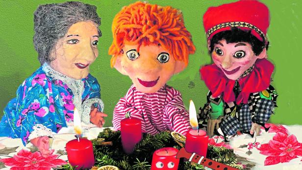 Drei Puppen sitzen an einem Tisch mit Adventskranz und brennenden Kerzen.