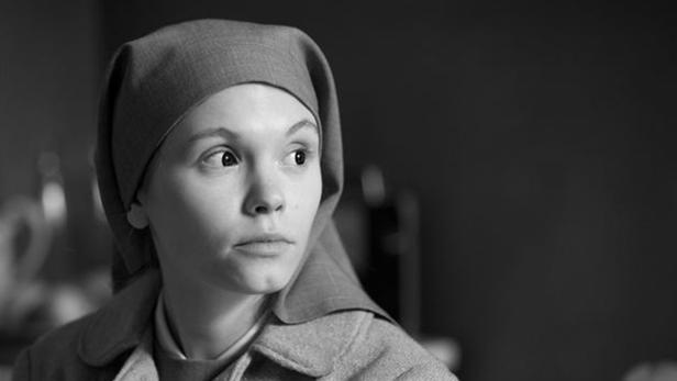 Schwarzweißporträt einer jungen Frau mit Haube, die nach rechts blickt.