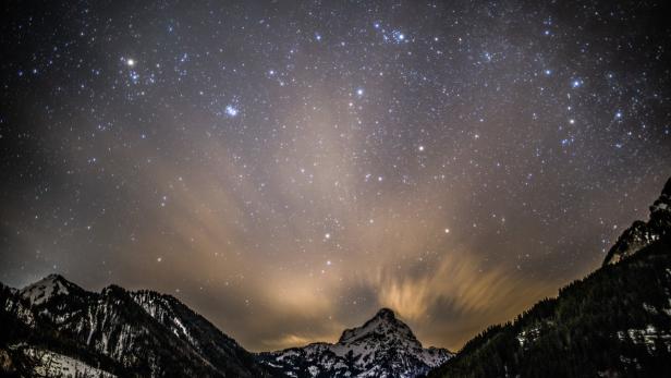 Sternenhimmel über einer verschneiten Berglandschaft.