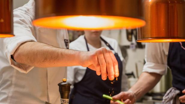 Ein Koch garniert Speisen in einer Restaurantküche.