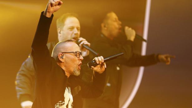 Eine Band tritt auf der Bühne auf, der Sänger mit Brille reckt die Faust in die Luft.