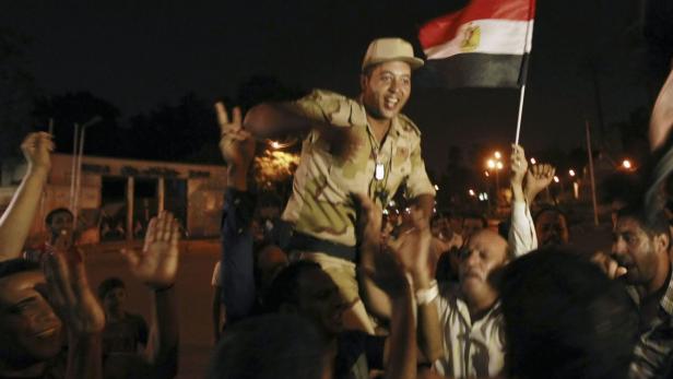 An army soldier (C) cheers with protesters, who are against Egyptian President Mohamed Mursi, as they dance and react in front of the Republican Guard headquarters in Cairo July 3, 2013. Egypt&#039;s armed forces overthrew elected Islamist President Mohamed Mursi on Wednesday and announced a political transition with the support of a wide range of political, religious and youth leaders. A statement published in Mursi&#039;s name on his official Facebook page after head of Egypt&#039;s armed forces General Abdel Fattah al-Sisi&#039;s speech said the measures announced amounted to &quot;a full military coup&quot; and were &quot;totally rejected&quot;. REUTERS/Louafi Larbi (EGYPT - Tags: POLITICS CIVIL UNREST MILITARY)