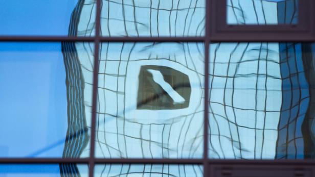 Die verzerrte Spiegelung des Logos der Deutschen Bank in einer Glasfassade.