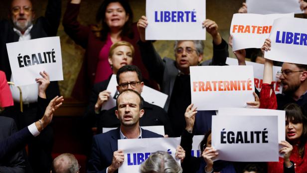 Mitglieder des französischen Parlaments protestieren mit Papierschildern gegen umstrittenes Immigrationsgesetz