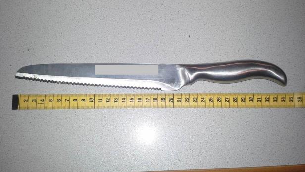 Ein Brotmesser liegt neben einem gelben Messband.