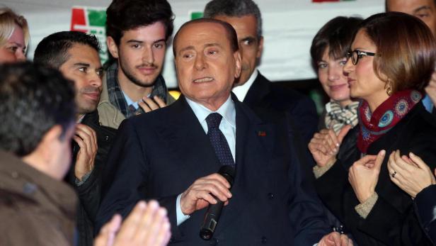 Silvio Berlusconi spricht bei einer Veranstaltung in ein Mikrofon.