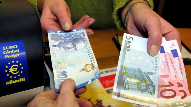 Eine Person hält einen Tausend-Schilling-Schein und Euro-Banknoten in der Hand.