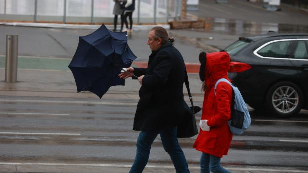 Mann kämpft bei Sturm mit Regenschirm