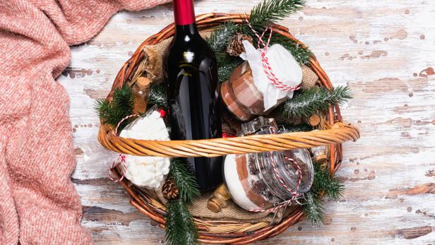 Rotwein und Konfektgläser in einem weihnachtlichen Präsentkorb.