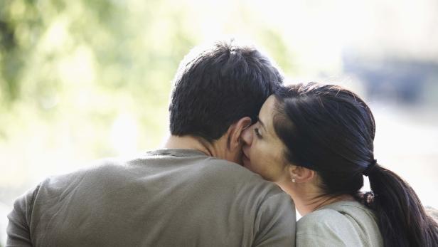 Eine Frau flüstert einem Mann etwas ins Ohr.