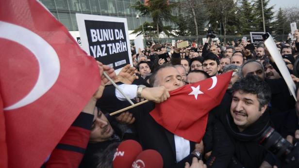 Einst Erdogan-Anhänger, heute Kritiker: „Zaman“-Chefredakteur (er küsst die türkische Fahne) wird von Polizisten in Zivil abgeführt.
